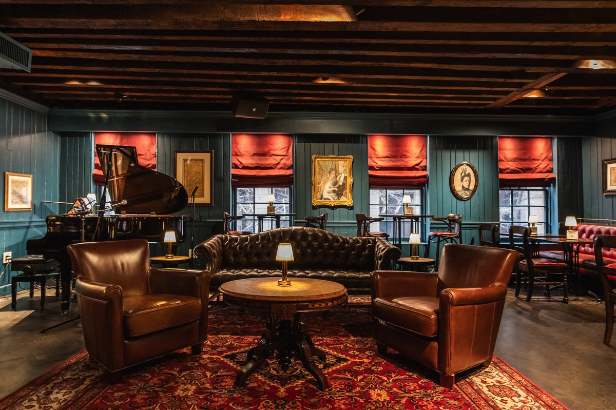 Elegant lounge with a grand piano, leather chairs, wooden tables.