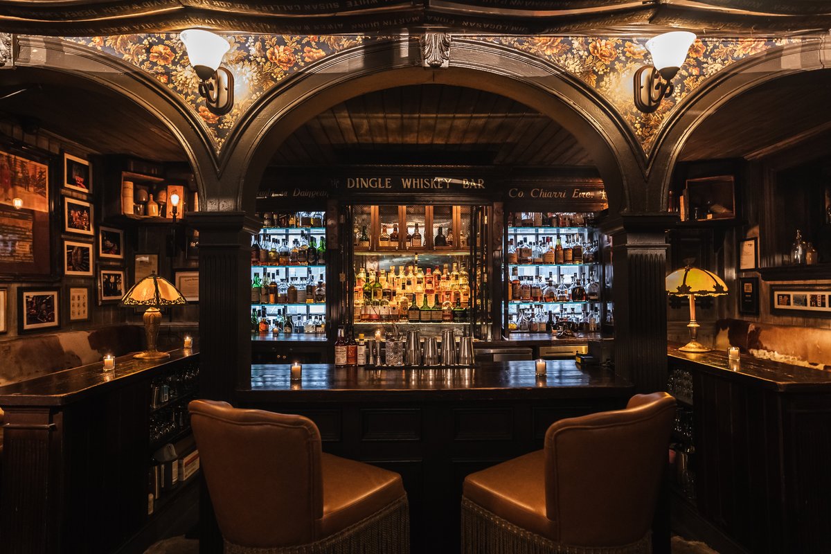 Bar with ornate wooden decor and shelves stocked with various bottles of whiskey.