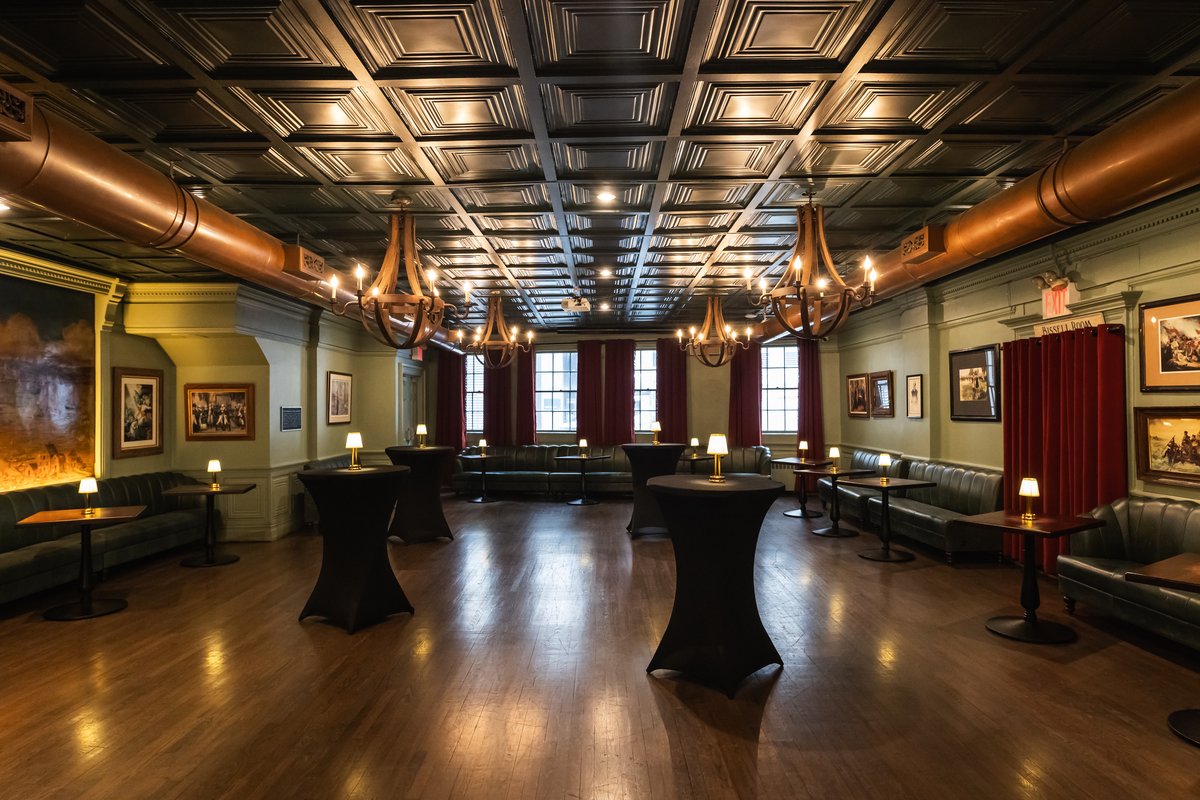 Classic room with a black-covered standing tables, couches along the walls, and chandeliers.